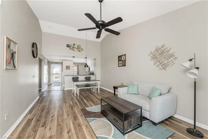 Living room with wood-type flooring, high vaulted ceiling, and ceiling fan