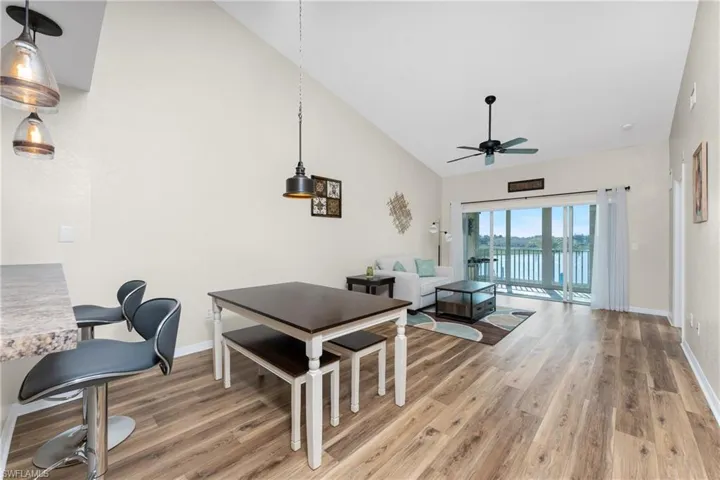 Dining area featuring wood-type flooring, a water view, ceiling fan, and high vaulted ceiling