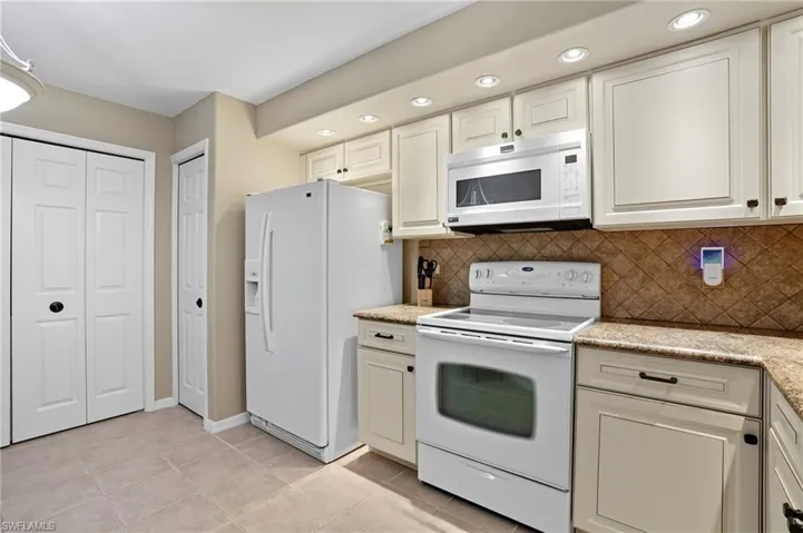 Kitchen featuring white cabinetry, integrated microwave, tile backsplash, and light-toned flooring