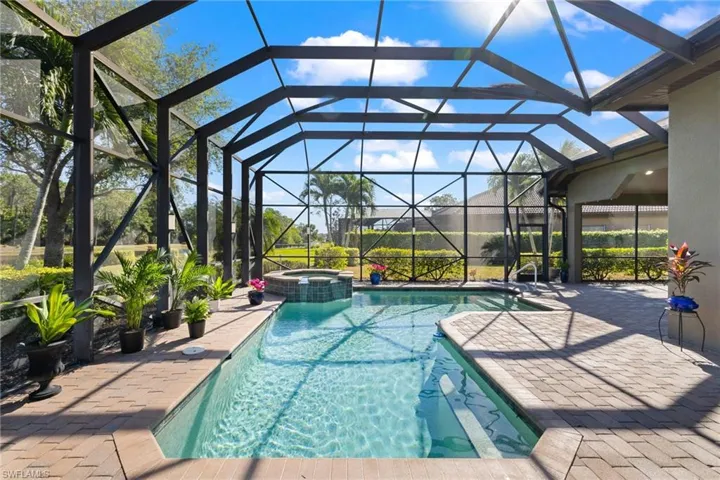 View of pool with an in ground hot tub, a patio, and glass enclosure