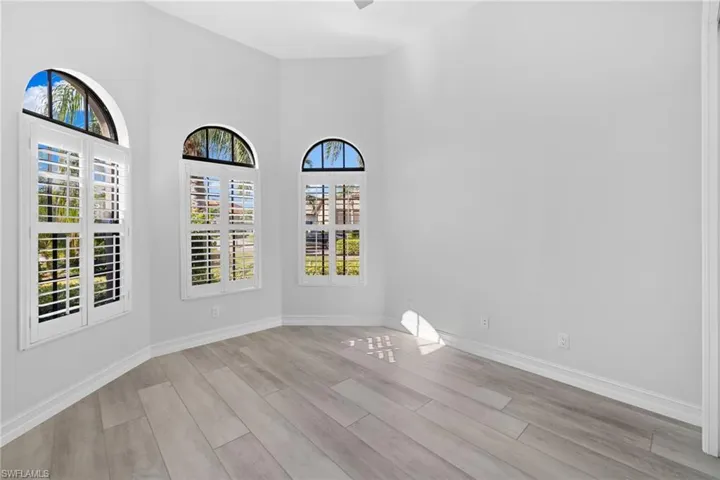 Unfurnished room featuring a healthy amount of sunlight, light wood-type flooring, and a high ceiling