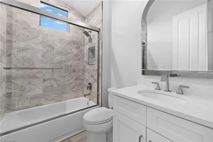 Full bathroom featuring vanity, enclosed tub / shower combo, and toilet