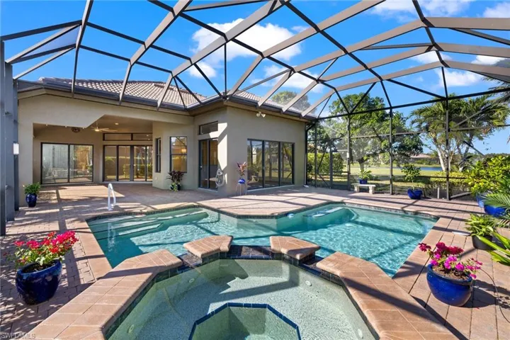 View of pool featuring an in ground hot tub, glass enclosure, and a patio area