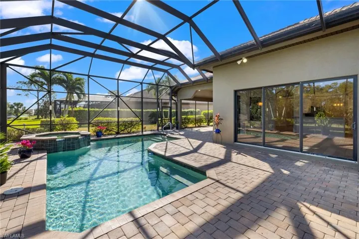View of pool featuring an in ground hot tub, glass enclosure, and a patio area