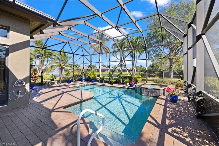 View of swimming pool with an in ground hot tub, glass enclosure, and a patio area
