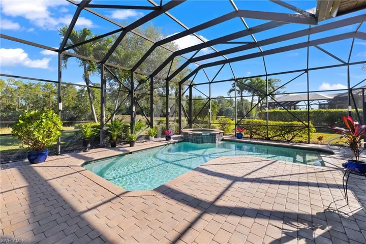 View of swimming pool featuring glass enclosure, an in ground hot tub, and a patio