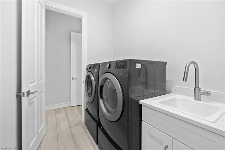 Laundry area with cabinets, washing machine and dryer, light hardwood / wood-style floors, and sink