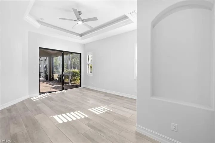 Unfurnished room with a raised ceiling, ceiling fan, and light hardwood / wood-style floors