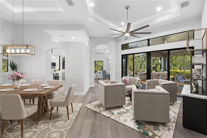 Living room featuring hardwood / wood-style floors, ceiling fan with notable chandelier, a raised ceiling, and a high ceiling
