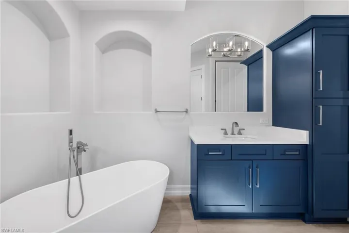 Bathroom featuring a chandelier, vanity, a tub, and tile patterned flooring