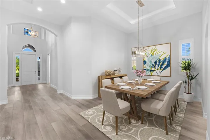 Dining room featuring a high ceiling, light hardwood / wood-style flooring, and a raised ceiling