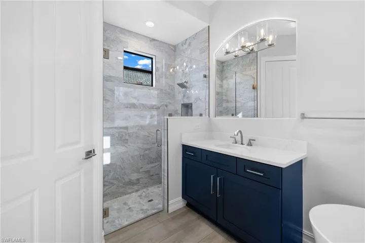 Bathroom featuring plus walk in shower, vanity, hardwood / wood-style flooring, and a chandelier