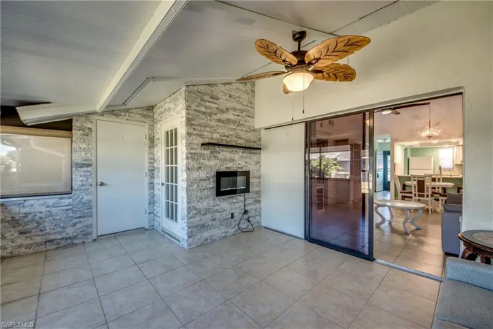 Unfurnished living room featuring ceiling fan, tile patterned floors, and a stone fireplace