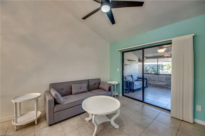 Living room featuring a ceiling fan, lofted ceiling, baseboards, and light tile patterned floors