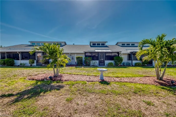 View of front facade featuring a sunroom, a front lawn, and central AC unit