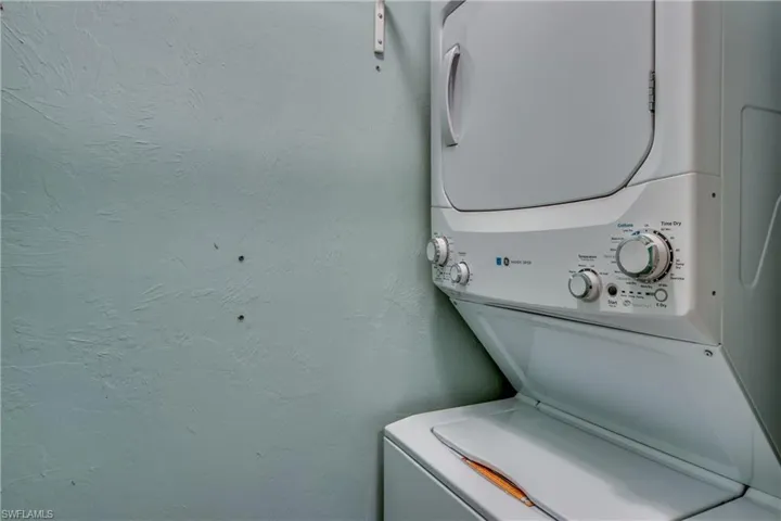 Laundry room featuring stacked washing machine and dryer and a textured wall