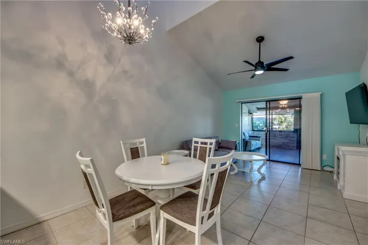 Dining room featuring vaulted ceiling, ceiling fan, light tile patterned flooring, a chandelier, and baseboards