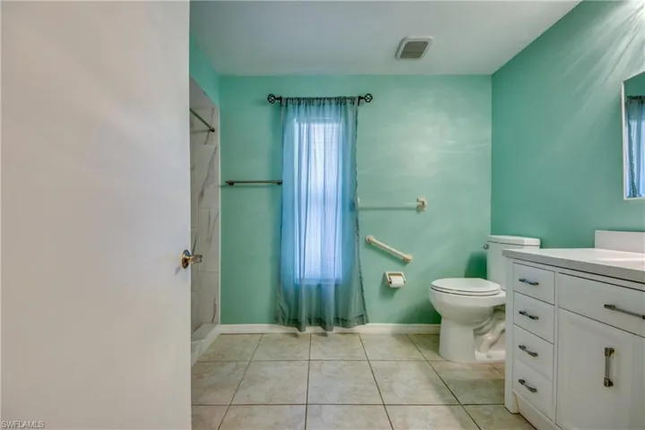 Bathroom featuring toilet, a shower, vanity, tile patterned flooring, and baseboards