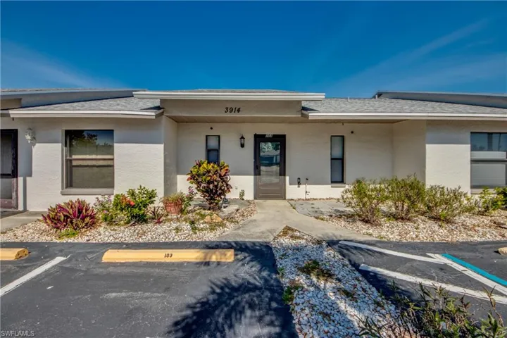 Doorway to property featuring uncovered parking, stucco siding, and a shingled roof