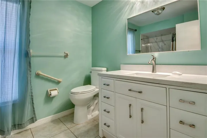 Bathroom with tile patterned flooring, toilet, vanity, a shower with curtain, and baseboards