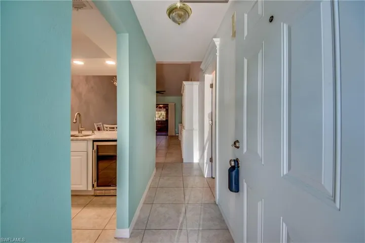 Corridor with a sink, wine cooler, light tile patterned floors, baseboards, and recessed lighting