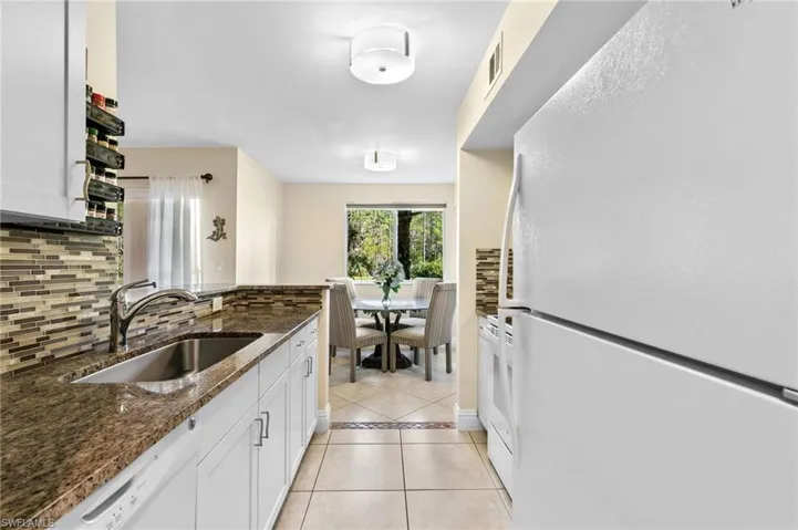 Kitchen featuring white cabinets, dark stone countertops, white appliances, sink, and decorative backsplash