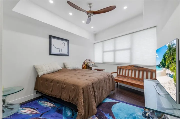 Bedroom with wood finished floors, ceiling fan, recessed lighting, and a raised ceiling