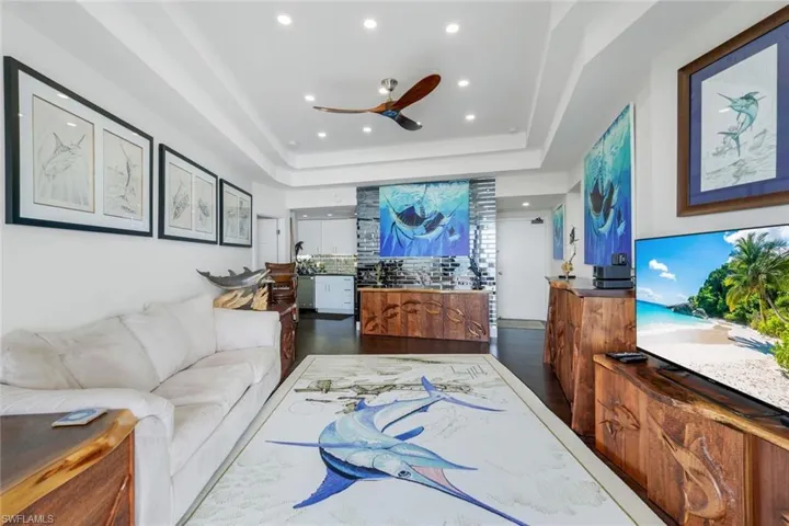 Living area featuring a ceiling fan, a tray ceiling, and recessed lighting