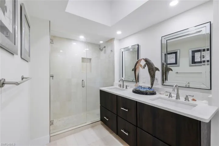 Bathroom featuring double vanity, a shower stall, recessed lighting, and light tile patterned flooring