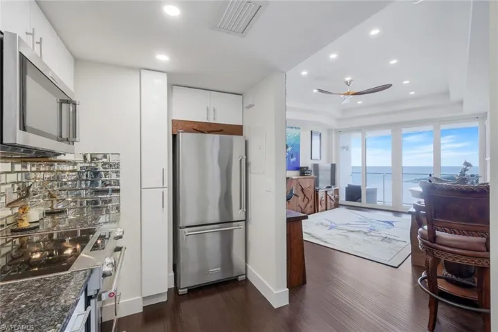 Kitchen featuring stainless steel appliances, dark wood finished floors, recessed lighting, white cabinetry, and a tray ceiling