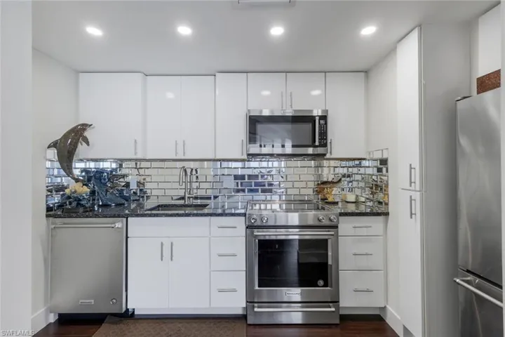 Kitchen featuring stainless steel appliances, dark stone counters, white cabinets, and recessed lighting