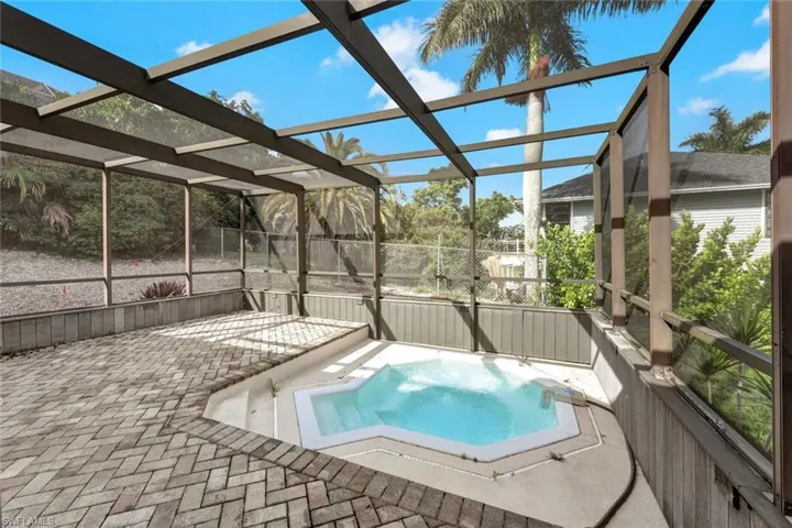 View of swimming pool with a hot tub, glass enclosure, and a patio area