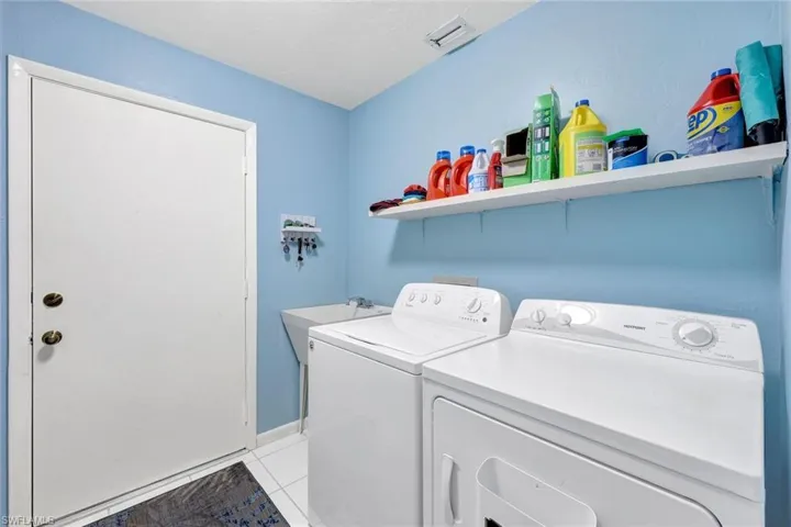 Laundry area with independent washer and dryer and light tile patterned floors