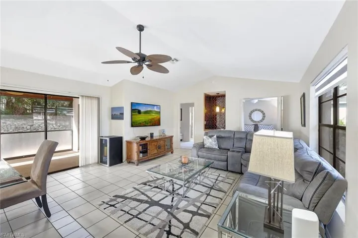 Living room featuring lofted ceiling, light tile patterned floors, and ceiling fan