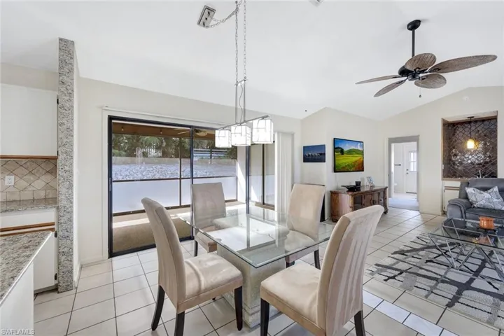 Dining space featuring light tile patterned flooring, ceiling fan, and vaulted ceiling