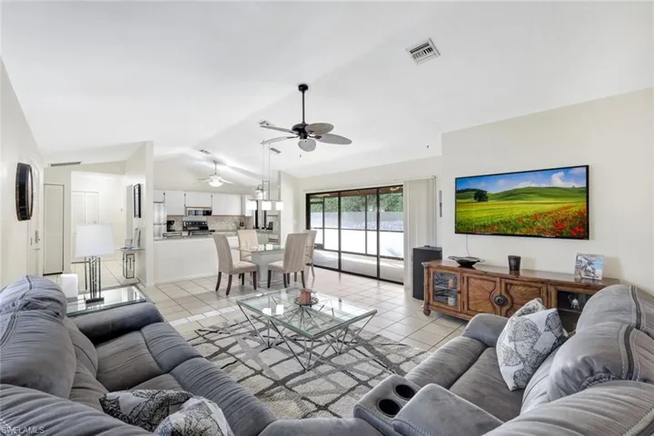 Tiled living room featuring ceiling fan and vaulted ceiling