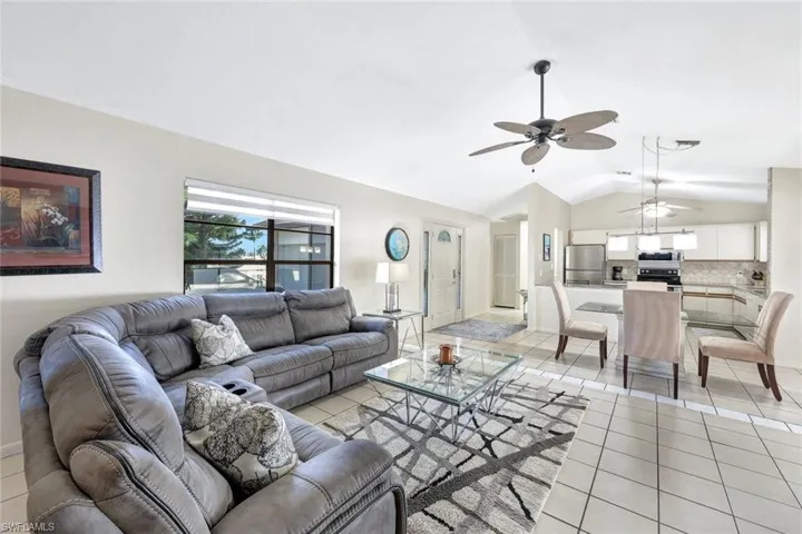 Living room featuring ceiling fan, vaulted ceiling, and light tile patterned floors