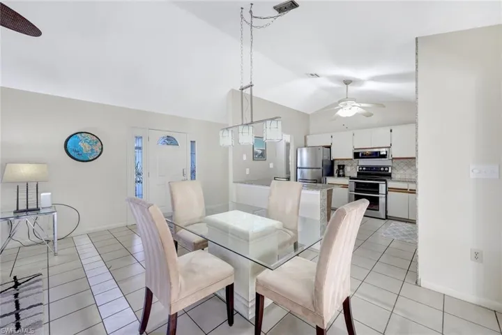 Dining room with lofted ceiling, light tile patterned floors, and ceiling fan