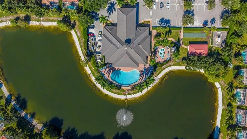Community center with a large roofline, multiple swimming pools, and a water feature in the adjacent lake