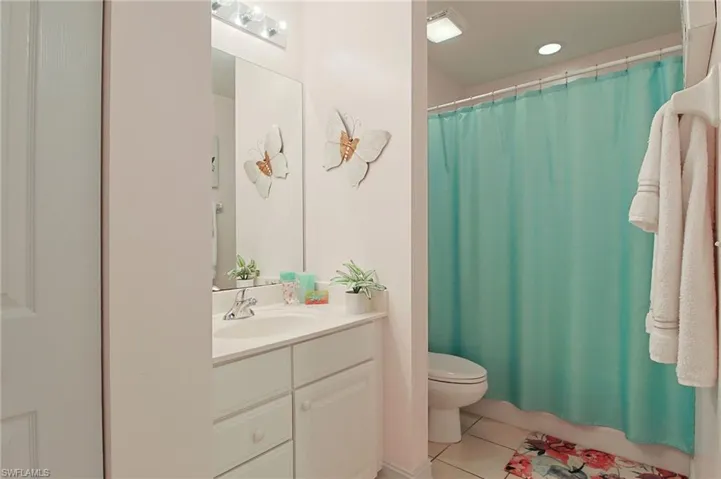 Bathroom with vanity, toilet, tile patterned floors, recessed lighting, and a shower with curtain