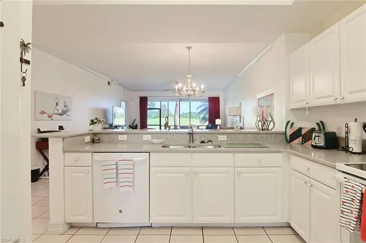 Kitchen with an inviting chandelier, a peninsula, white appliances, a sink, and light tile patterned floors