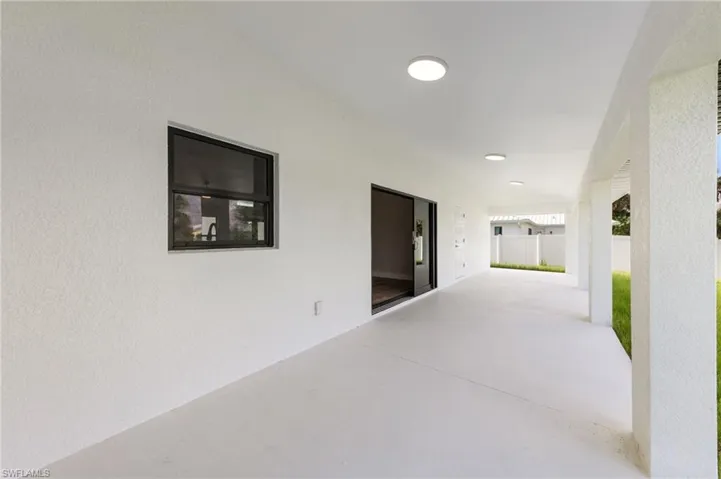 Expansive covered patio featuring a clean concrete surface, recessed lighting, and a white stucco finish