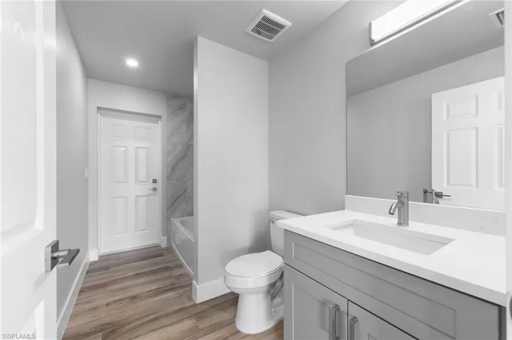Bathroom featuring a grey vanity with a white countertop, an integrated sink, and a large wall mirror