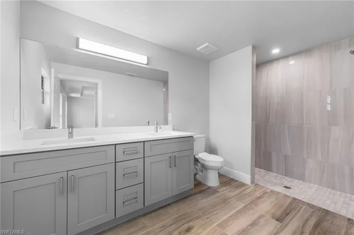 Bathroom featuring a dual vanity with light gray cabinetry, white countertops, and integrated sinks