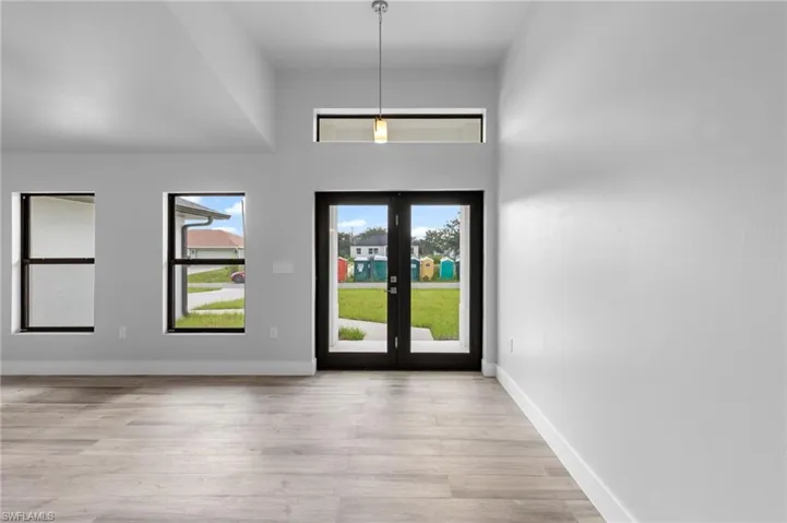 Entryway featuring double glass-paneled doors, wood-finish flooring, and a vaulted ceiling