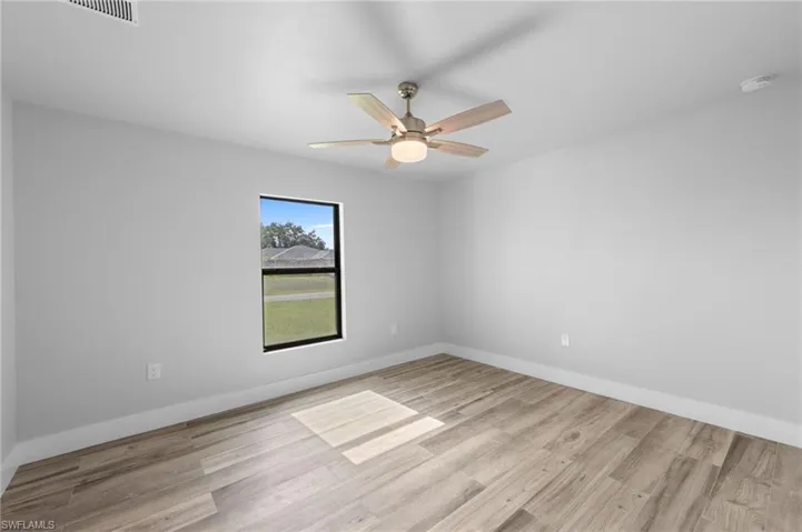Room featuring neutral walls, wood-finish flooring, and a ceiling fan with light fixture