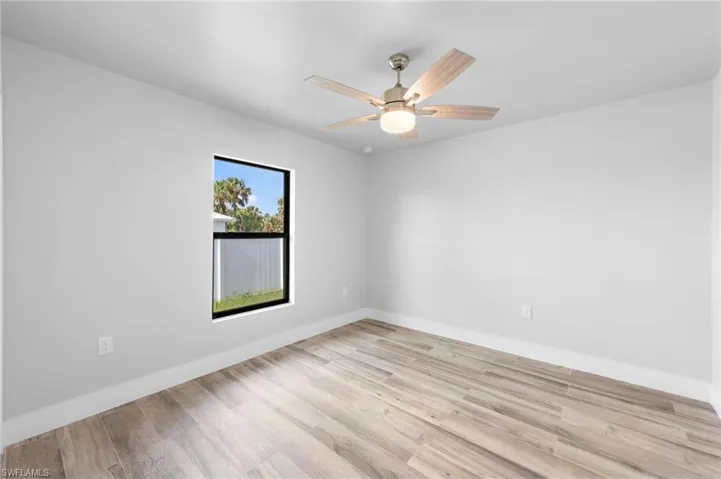 Room featuring light wood-finish flooring, a contemporary ceiling fan with integrated lighting, and a black-framed window