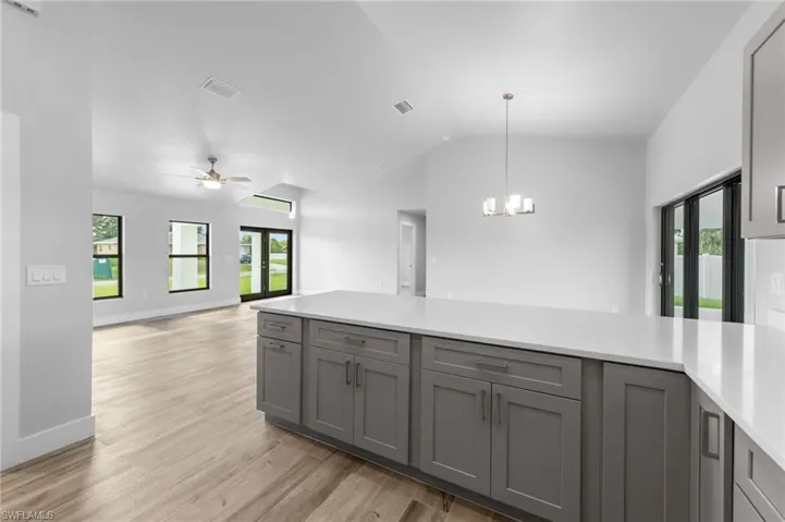 Kitchen island with a white countertop and gray cabinetry, featuring a contemporary chandelier
