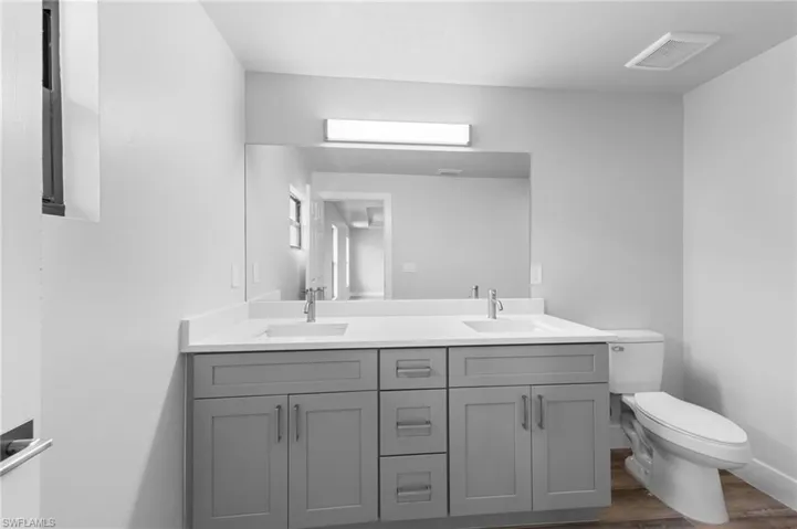 Dual sink vanity with light gray shaker cabinetry and white countertops
