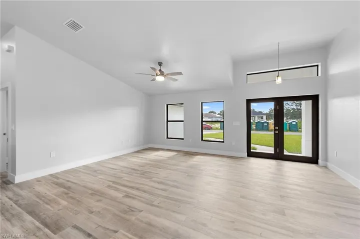 Spacious room featuring vaulted ceilings, wood-finish flooring, and contemporary light fixtures